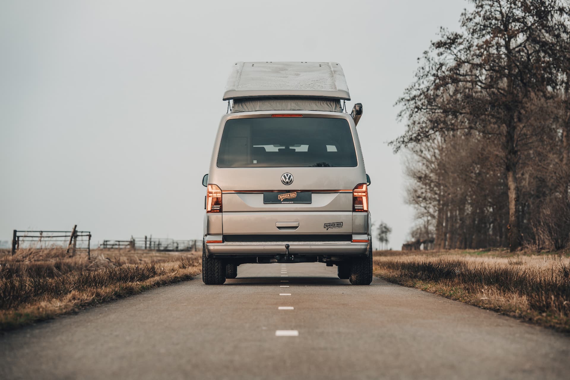 Achteraanzicht van een camper op een smalle weg